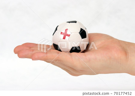 Mini football in hand and one black point of football is England flag. 70177452