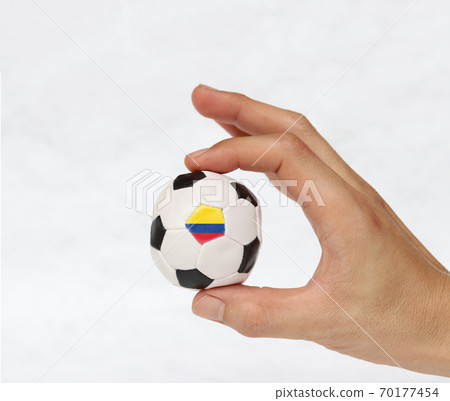 Mini football in hand and one black point of football is Colombia flag 70177454