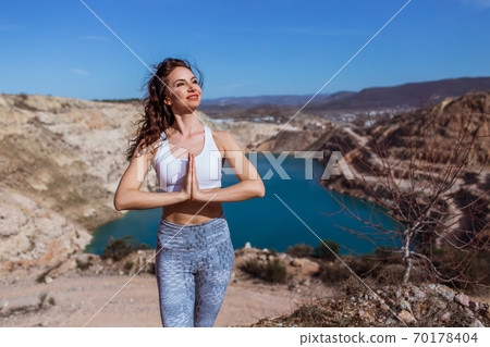 Young pretty woman is practicing yoga at mountain lake in shape of heart. Young pretty woman is practicing yoga at mountain lake in shape of heart. 70178404