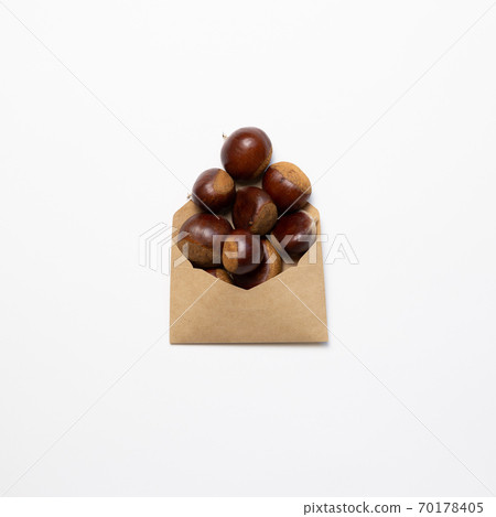 Chestnuts in a paper bag on white background. Autumn and winter snacks. top view, copy space 70178405