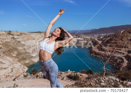 Young pretty woman is practicing yoga at mountain lake Young pretty woman is practicing yoga at mountain lake 70178427