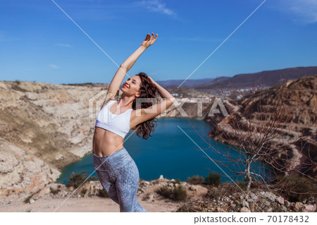 Young pretty woman is practicing yoga at mountain lake Young pretty woman is practicing yoga at mountain lake 70178432