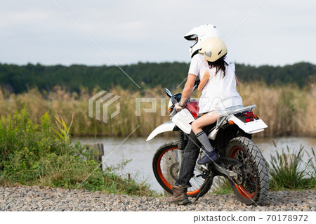 Father and daughter riding two-seater off-road bike Father and daughter riding two-seater off-road bike 70178972