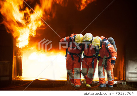 Firefighters are helping workers by pulling out of the burning building. 70183764