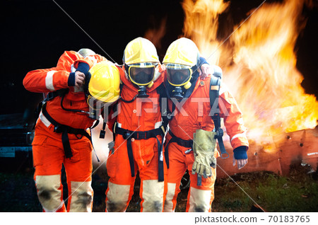 Firefighters are helping workers by pulling out of the burning building. 70183765