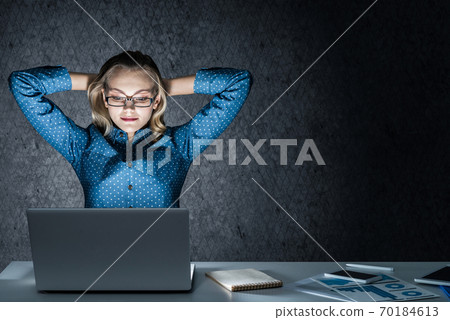 Attractive blonde working on laptop in dark office. Mixed media Attractive blonde working on laptop in dark office. Mixed media 70184613