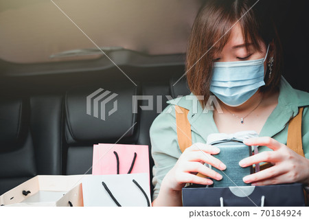 new normal and social distancing concept with asian woman shopping and prepare new year gift in her car and wear protective mask new normal and social distancing concept with asian woman shopping and prepare new year gift in her car and wear protective mask 70184924
