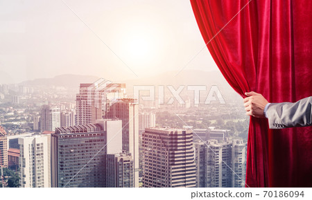 Modern business cityscape behind curtain opened by businessman hand Modern business cityscape behind curtain opened by businessman hand 70186094