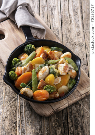 Stir fry chicken with vegetables on iron pan on wooden table Stir fry chicken with vegetables on iron pan on wooden table 70186717