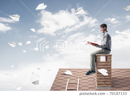 Handsome student guy reading book and paper planes flying in air Handsome student guy reading book and paper planes flying in air 70187133