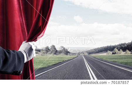 Asphalt road behind red curtain and hand holding it 70187857