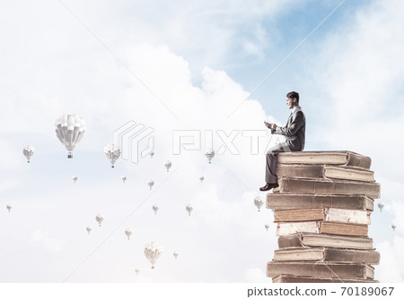 Man businessman on stack reading book and aerostats flying aroun Man businessman on stack reading book and aerostats flying aroun 70189067
