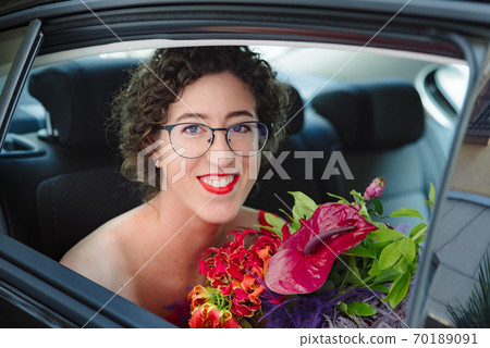 The bride in glasses looks out of the car. The bride in glasses looks out of the car. 70189091