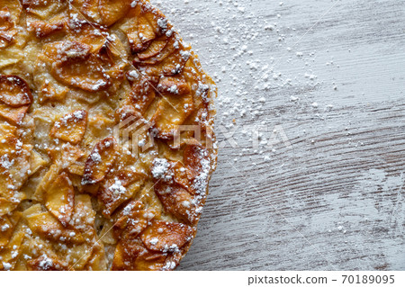 Homemade baking. Freshly baked apple pie on a light wooden background sprinkled with icing sugar. Homemade baking. Freshly baked apple pie on a light wooden background sprinkled with icing sugar. 70189095