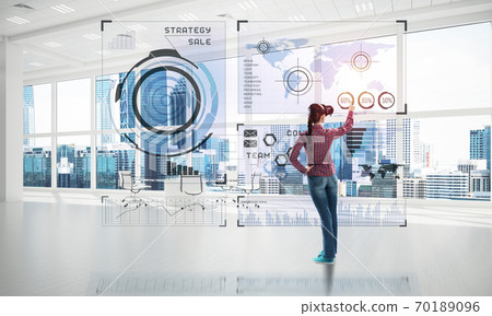 Girl in office interior in virtual reality mask using innovative technologies. Mixed media Girl in office interior in virtual reality mask using innovative technologies. Mixed media 70189096