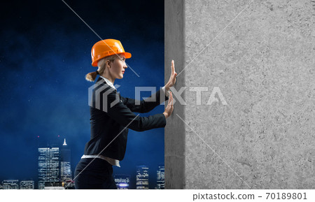 Beautiful woman architect pushing concrete wall Beautiful woman architect pushing concrete wall 70189801