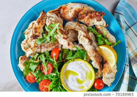 Grilled chicken with arugula salad on a blue plate 70189965