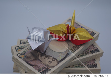 A bundle of bills piled up in a spiral staircase and a pair of folded paper cranes A bundle of bills piled up in a spiral staircase and a pair of folded paper cranes 70190284
