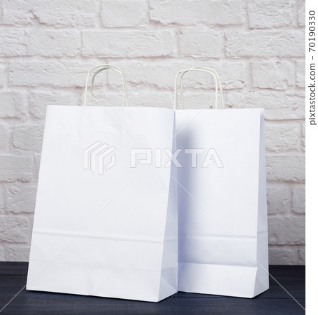 white paper bag with handles on white brick wall background, environmental material 70190330