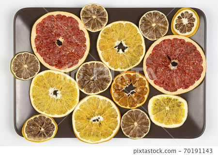 Dried pieces of various citrus fruits lie on a brown plate Dried pieces of various citrus fruits lie on a brown plate 70191143