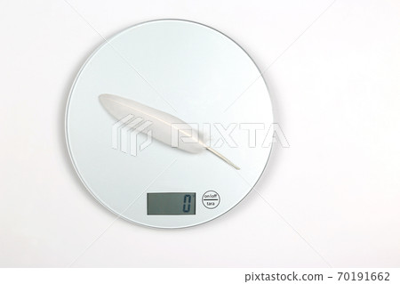 white bird feather is weighed on a digital scale. white bird feather is weighed on a digital scale. 70191662