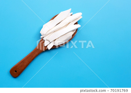 Dried Chinese Yam on wooden spoon on blue background. Dried Chinese Yam on wooden spoon on blue background. 70191769