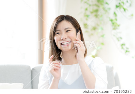 A woman talking on a smartphone [living room] 70195283