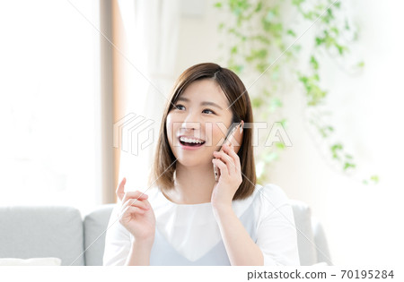 A woman talking on a smartphone [living room] 70195284