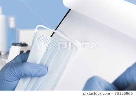 Hand holding disposable face mask with white notepaper Hand holding disposable face mask with white notepaper 70196966