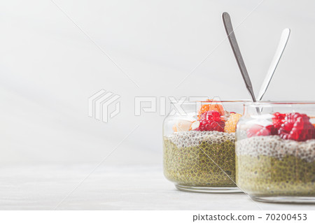 Chia pudding with matcha tea and berries in glass jar, white background. Healthy food concept. 70200453