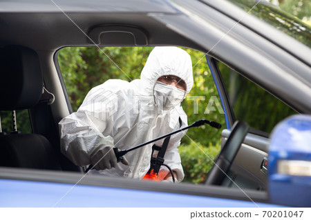 Virologist man wearing PPE kits kills bacteria and viruses inside the car. Virologist man wearing PPE kits kills bacteria and viruses inside the car. 70201047