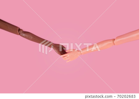 Two doll hands reach for each other on pink background. Different skin tones and races. Stop racism, diversity and unity, equality and feminism creative concept. Place for text, top view, layout Two doll hands reach for each other on pink background. Different skin tones and races. Stop racism, diversity and unity, equality and feminism creative concept. Place for text, top view, layout 70202683