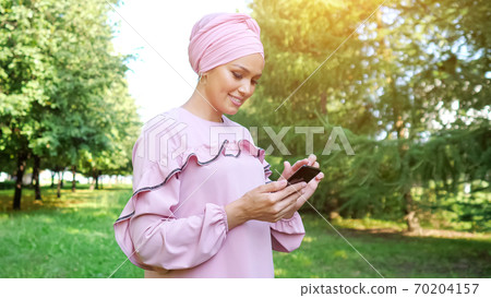 young woman in purple dress and hijab types on smartphone young woman in purple dress and hijab types on smartphone 70204157