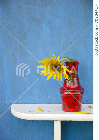 red vase with one sunflower blossom 70204417