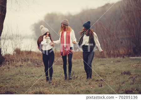 Thre friends walks in a winter park without snow Thre friends walks in a winter park without snow 70205136
