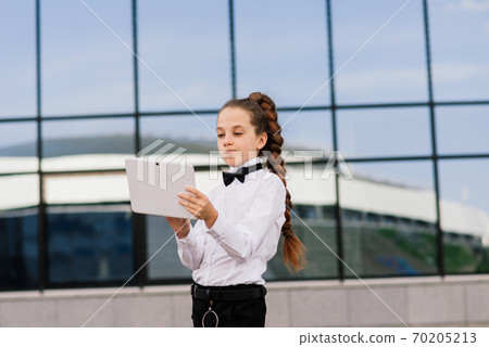 Young schoolgirl in a white classical blouse posing in the city Young schoolgirl in a white classical blouse posing in the city 70205213