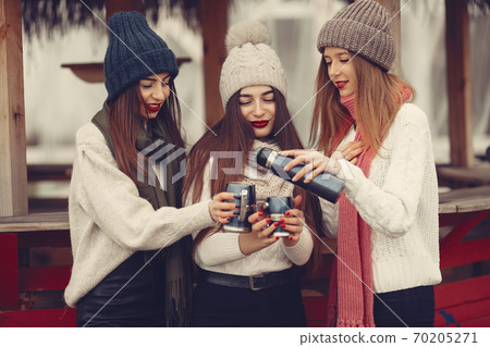 Women in a winter park without snow with thermos and tea 70205271