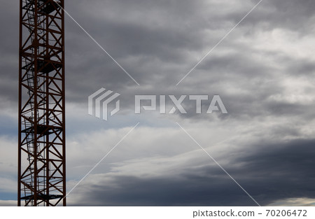 part of a construction crane against a blue sky with clouds, evening part of a construction crane against a blue sky with clouds, evening 70206472