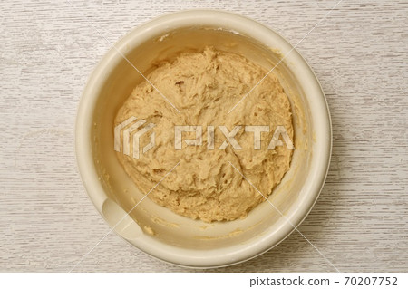 Mixed mixture of yeast dough ingredients, ready for lifting. The process of cooking in a light round large plastic bowl. Mixed mixture of yeast dough ingredients, ready for lifting. The process of cooking in a light round large plastic bowl. 70207752