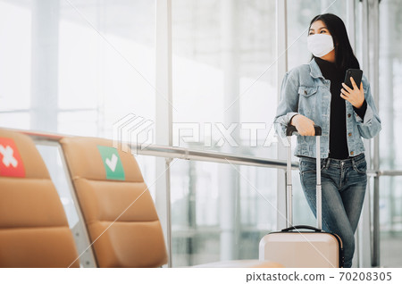 woman traveler wearing mask holding smartphone woman traveler wearing mask holding smartphone 70208305