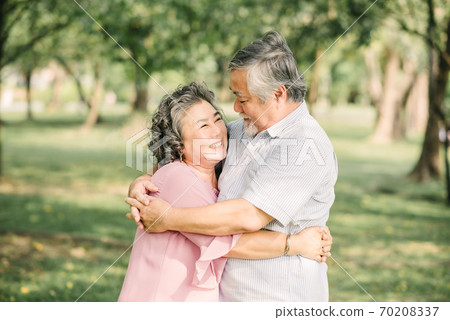 Happy senior Asian couple hugging outdoor in park Happy senior Asian couple hugging outdoor in park 70208337