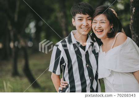 Two woman hugging while laughing and smiling outdoor in the park Two woman hugging while laughing and smiling outdoor in the park 70208343