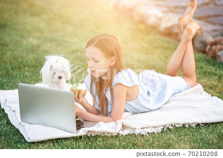 Little girl outdoors in the park with computer 70210208