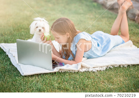 Little girl outdoors in the park with computer 70210219