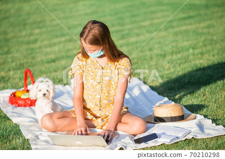 Little girl with dog wearing protective medical mask for prevent virus outdoors in the park 70210298