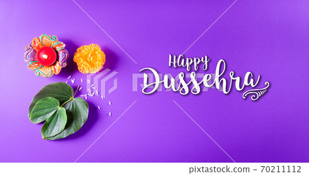 Happy Dussehra. Yellow flowers, green leaf and rice on purple pastel background. Dussehra Indian Festival concept. Happy Dussehra. Yellow flowers, green leaf and rice on purple pastel background. Dussehra Indian Festival concept. 70211112