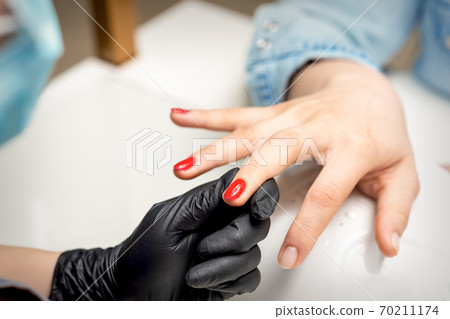 Young woman receives red nail polish 70211174