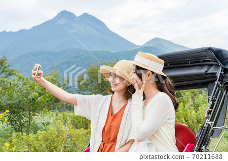 一名年輕女子和一位朋友在女孩出遊時用智能手機拍紀念照[9月] 70211688
