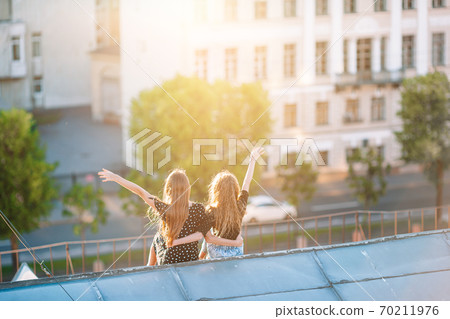 Cute girlson rooftop enjoying with view of beautiful sunset in Sankt Petersburg in Russia 70211976