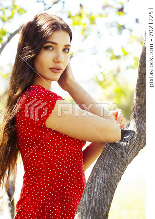 pretty young woman in red dress smiling cheerful in green park at tree on summer sunny day, lifestyle people concept 70212251
